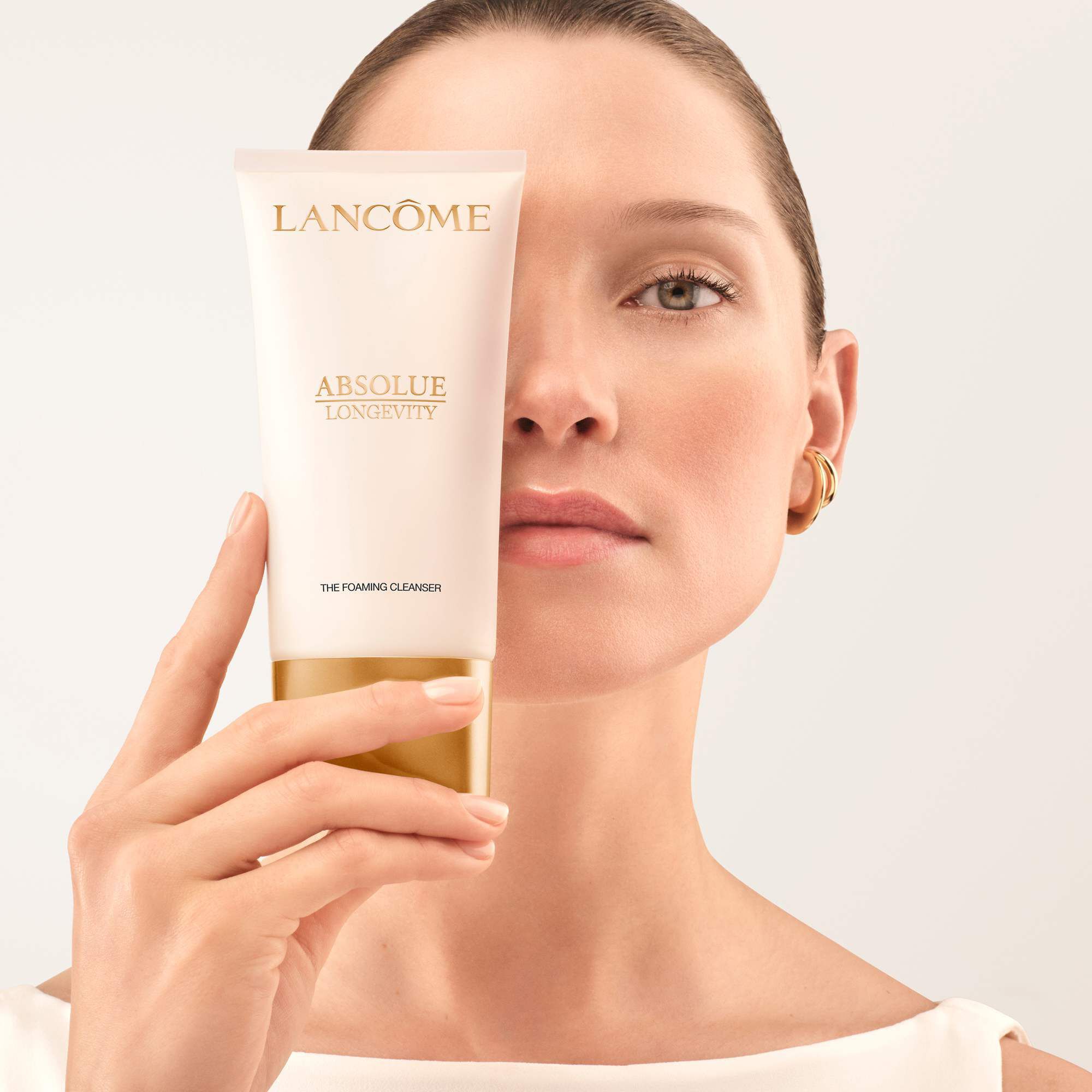 Model holding Absolue Longevity Foaming cleanser close to her face
